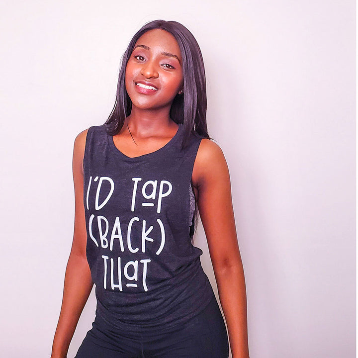 Woman wearing a black muscle tank that says '" I'd Tap (Back) That" in white text