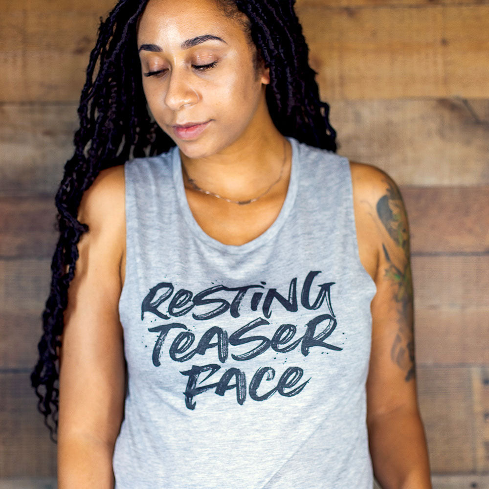 Woman wearing a grey tank top that says "resting teaser face" in black text