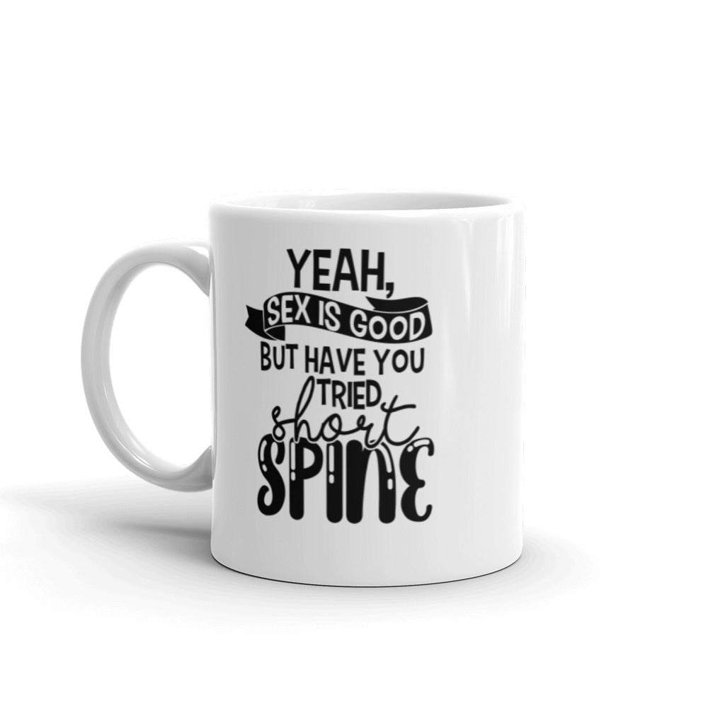 11 oz white coffee mug with handle on the left side. On the mug says " yeah, sex is good but have you tried short spine". Background is white. 