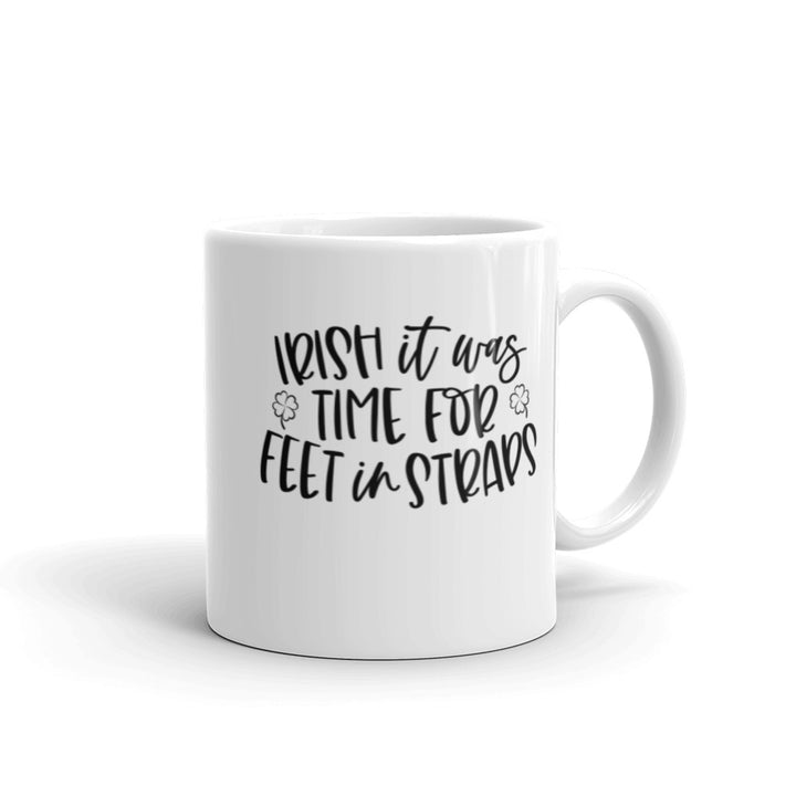 11 oz white coffee mug that says "Irish It Was Time For Feet In Straps" in black text. There are two black outline of 4 leaf clover on the front of the mug.