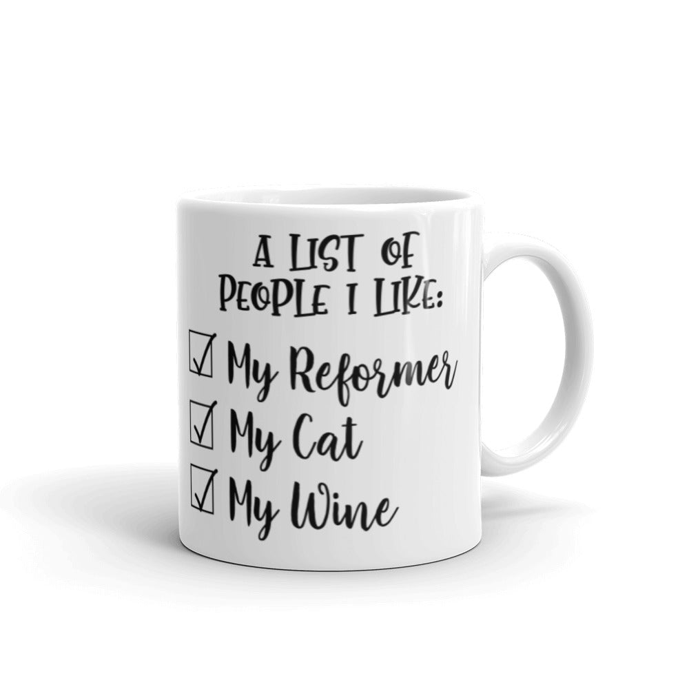 11 oz white coffee mug that says "A list of people I like: My reformer, My Cat, My Wine". 