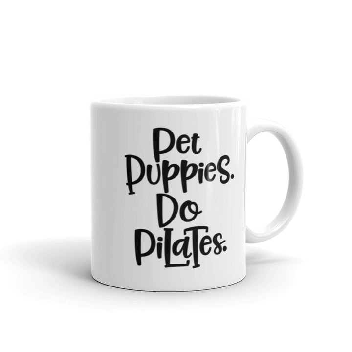 11 oz white mug that has the words "Pet Puppies. Do Pilates" on the front.