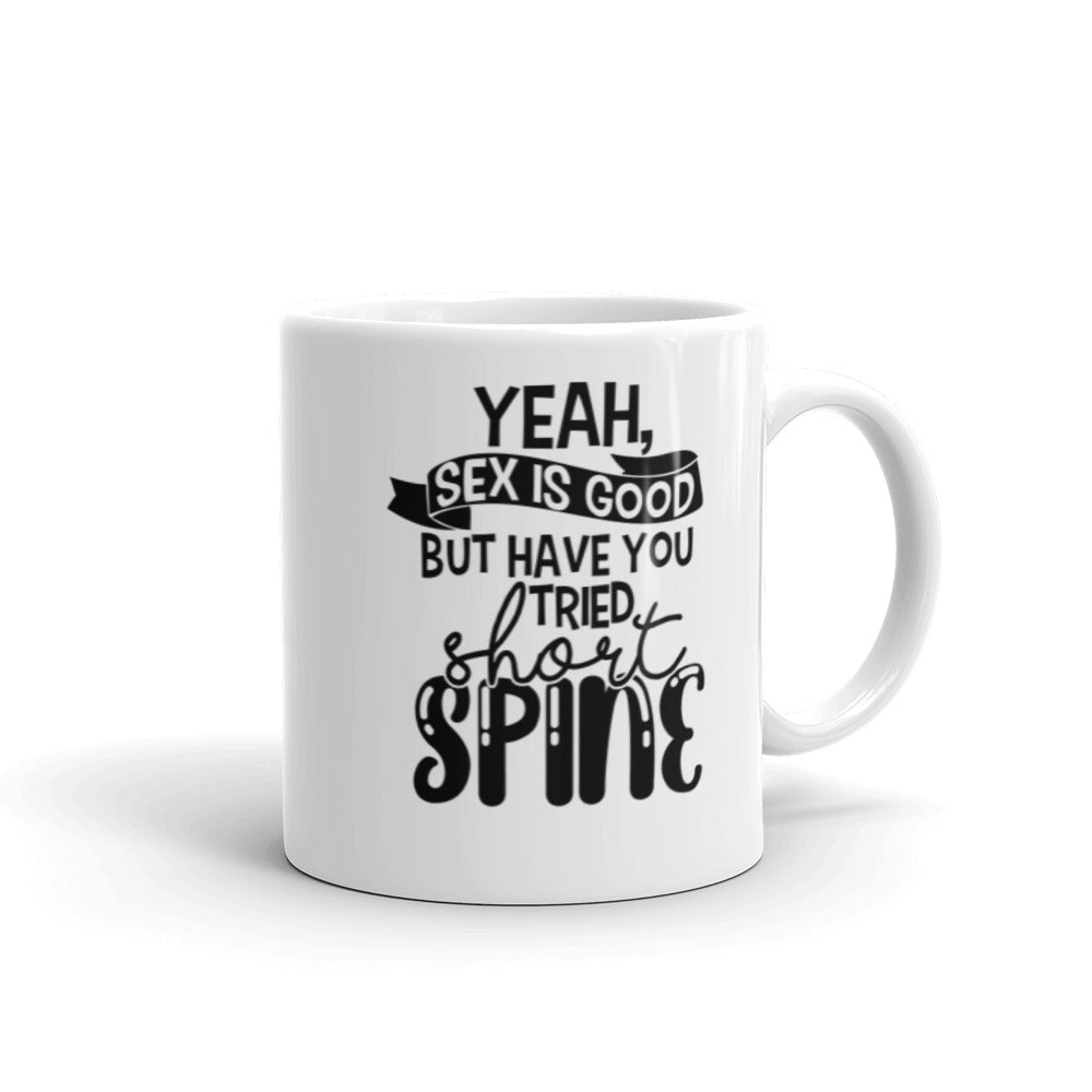 11 oz white coffee mug with handle on the right side. On the mug says " yeah, sex is good but have you tried short spine". Background is white. 