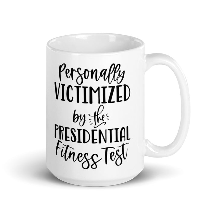 15 oz white ceramic mug that says "Personally victimized by the presidential fitness test" 